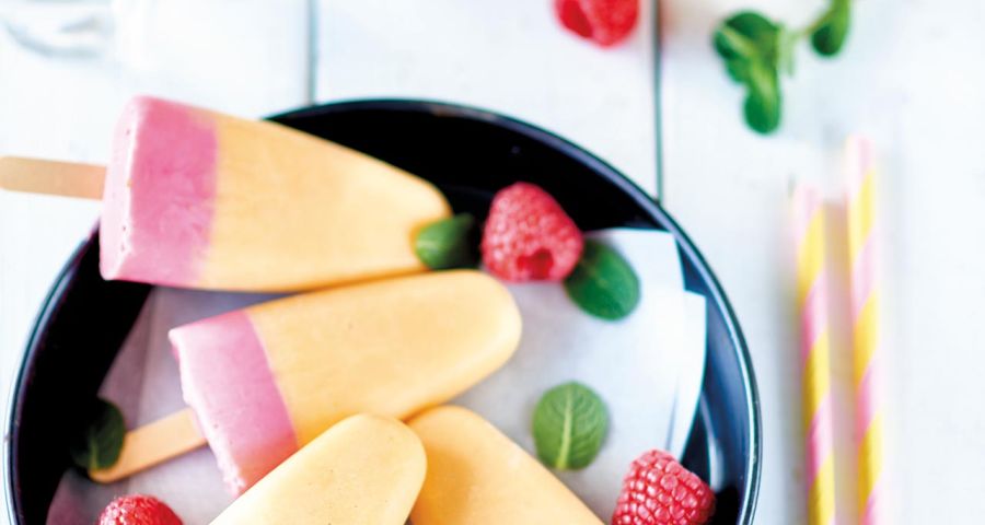 Two-tone ice lollies with yoghurt, raspberries and peaches